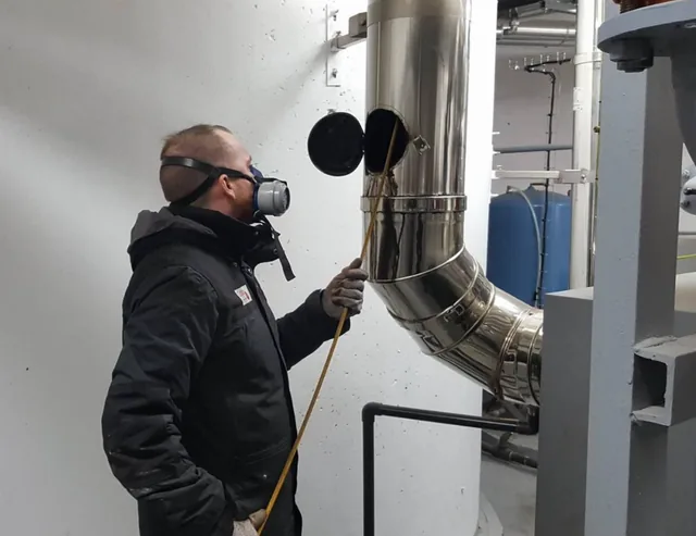 Technicien Terrier sur le conduit inox d'une chaufferie collective